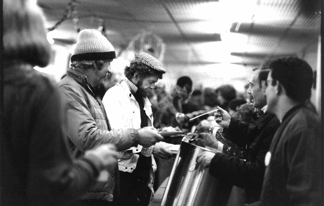 A black and white archival photograph of guests queuing for food at an early Crisis at Christmas.