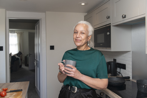 Yasmin is standing in her kitchen holding a mug of tea.