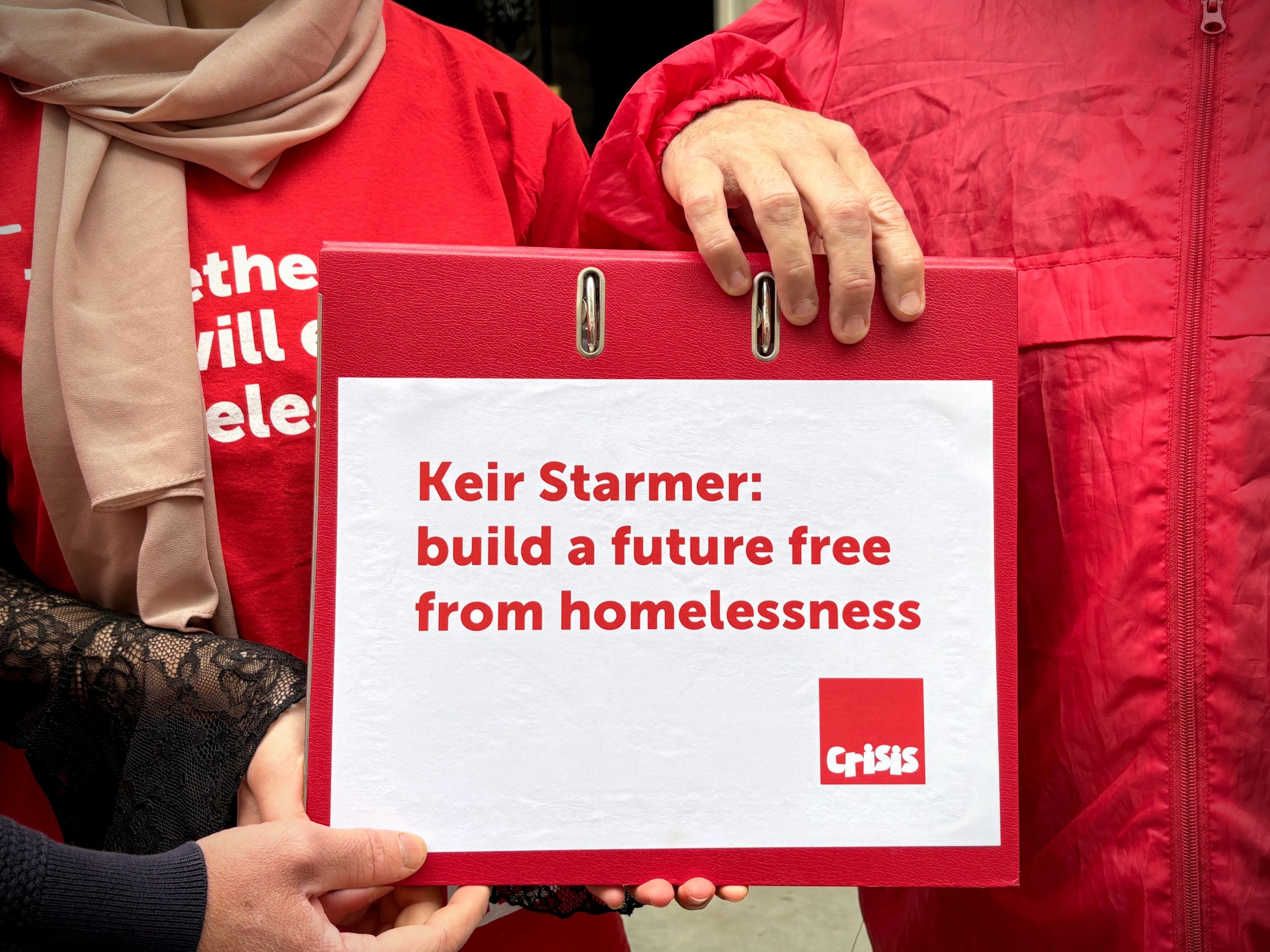 The hands of three people holding a folder that says: 'Keir Starmer: build a future free from homelessness'