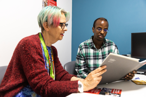 Two people are looking over a leaflet in a meeting room