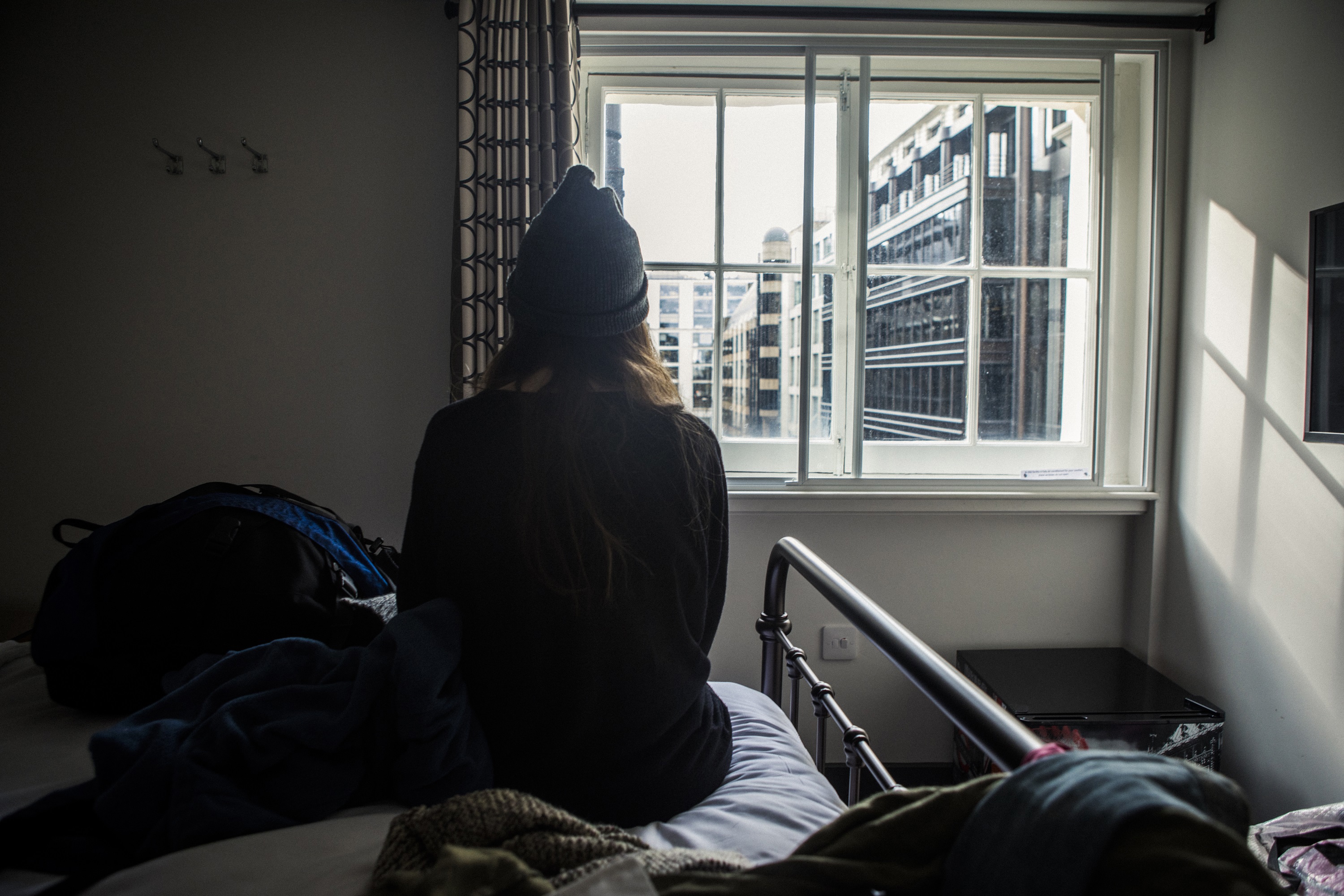 Woman sitting on a bed looking out of window