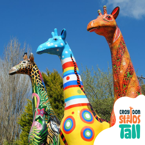 Three brightly coloured giraffe sculptures with Croydon Stands Tall logo