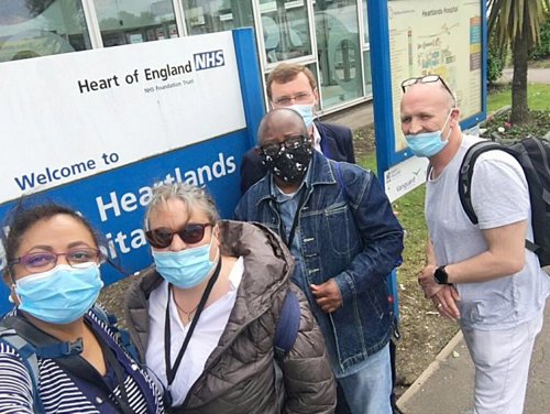 Five volunteers wearing masks stood outside the Heartlands Hospital Welcome sign