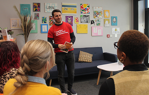 A volunteer stands at the front of the room speaking to a group. 