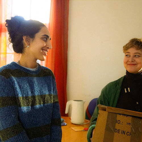 two women smiling together as they move into a new home