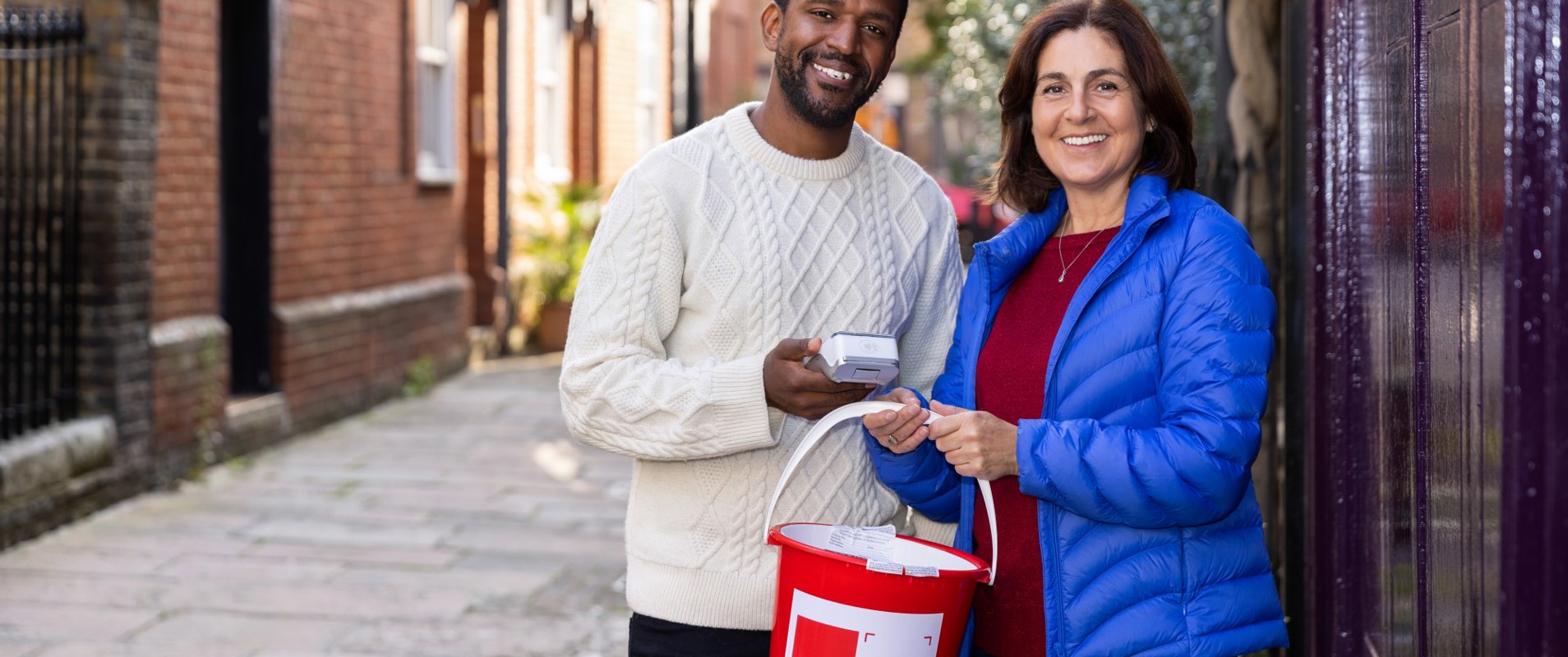 Two volunteers taking part in a bucket collection on a street