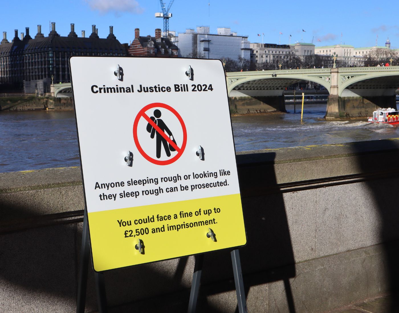 An imitation road sign standing in front of the River Thames