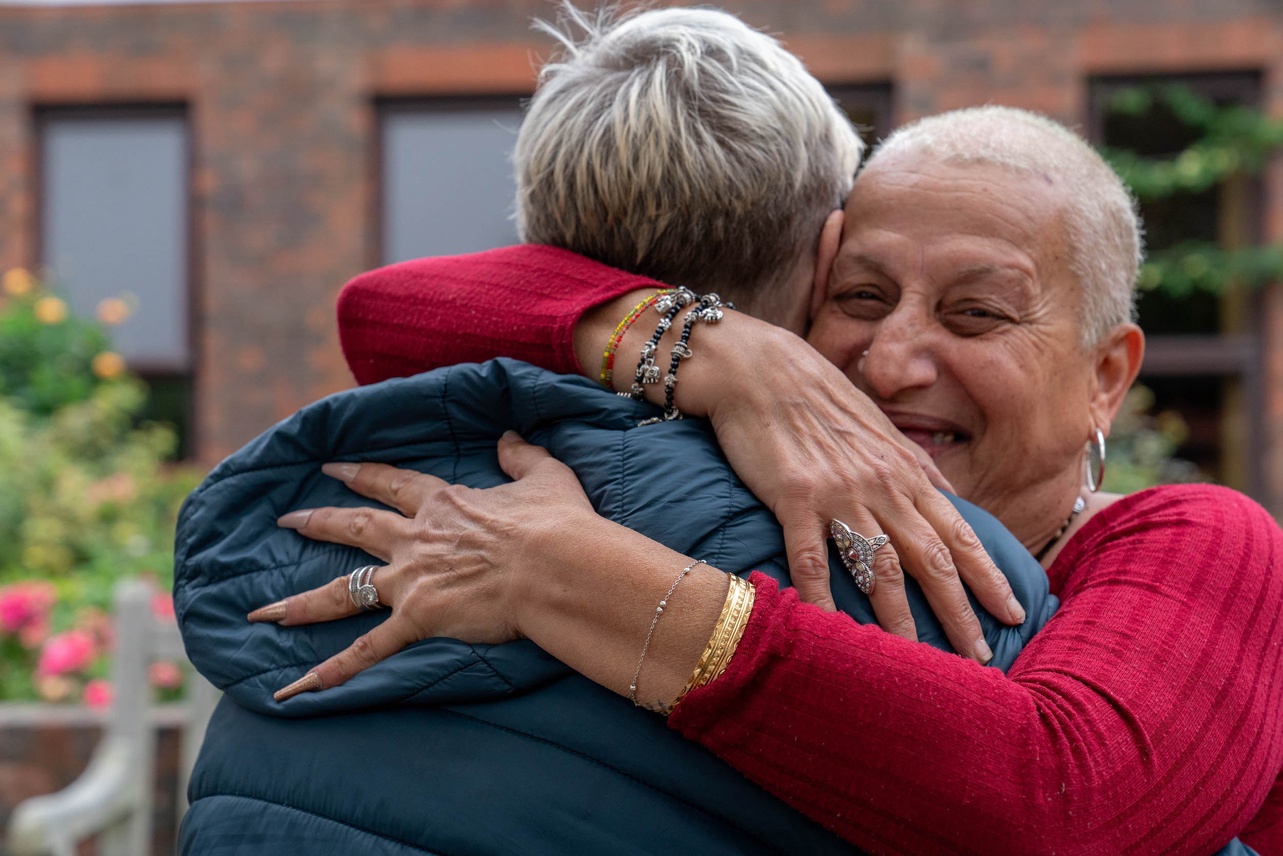 two women greet each other warmly hugging