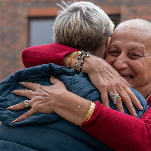 two women greet each other warmly hugging