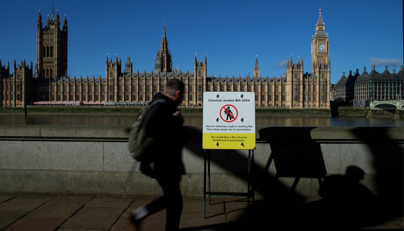 A man looks at an imitation road sign with the Palace of Westminster in the background