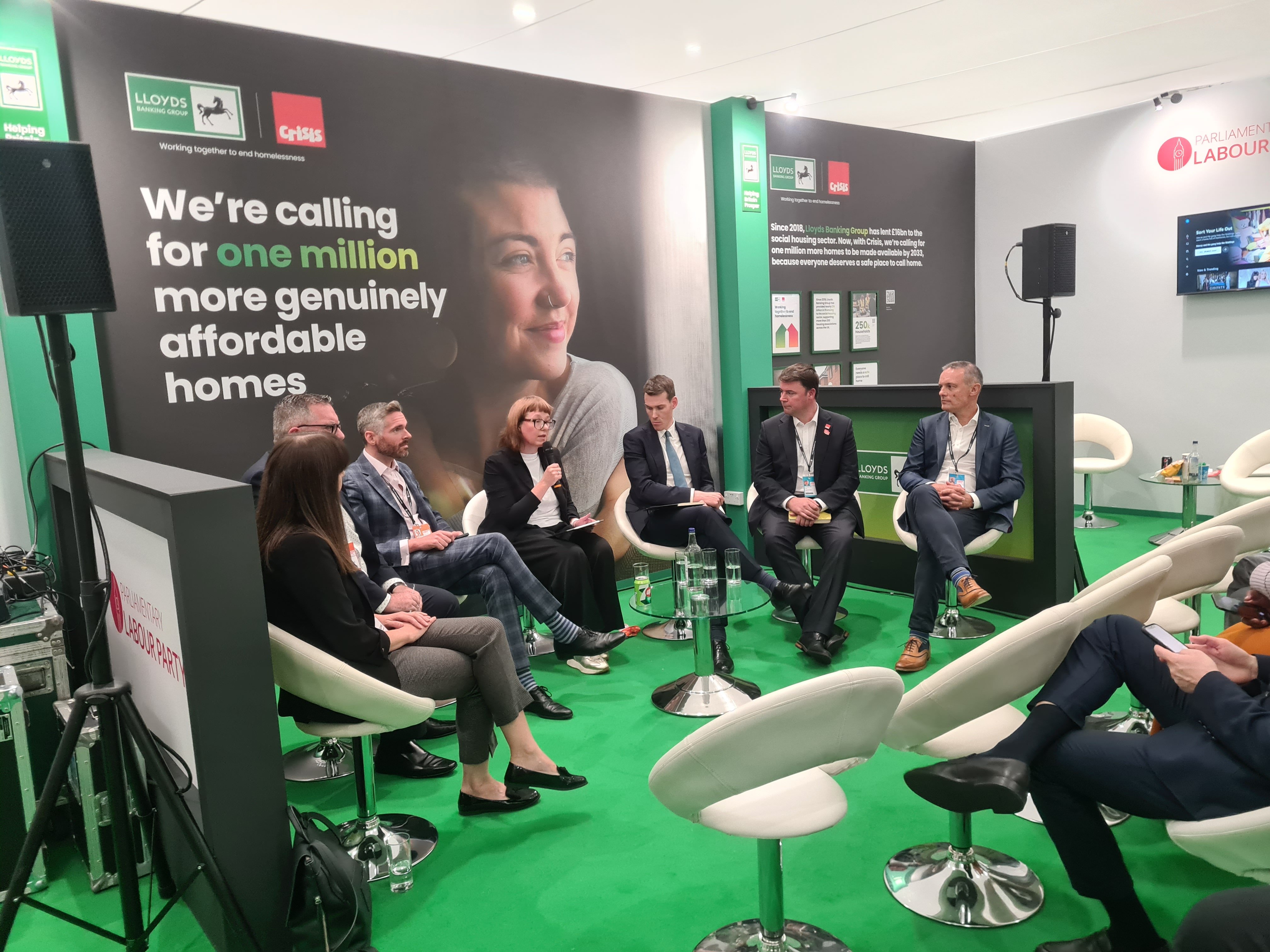Seven panellists sit in front of a Crisis and Lloyds Banking Group branded campaign banner.